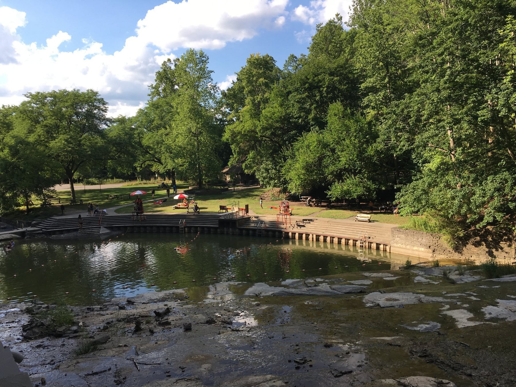 Summer swim area, stone ledges, and picnic lawn at Buttermilk Falls in Connecticut.