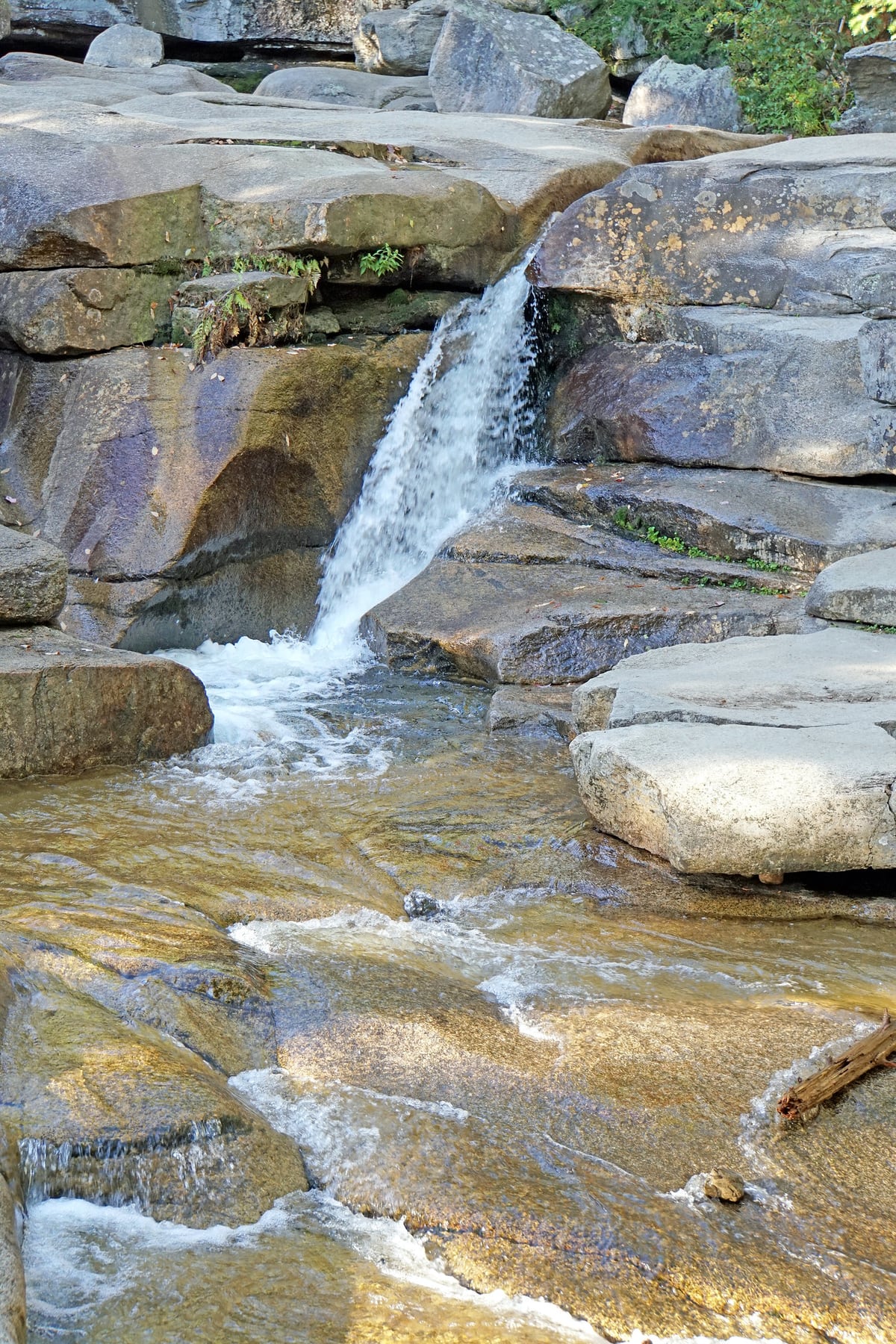 A narrow waterfall dropping through polished granite ledges at Diana's Baths.