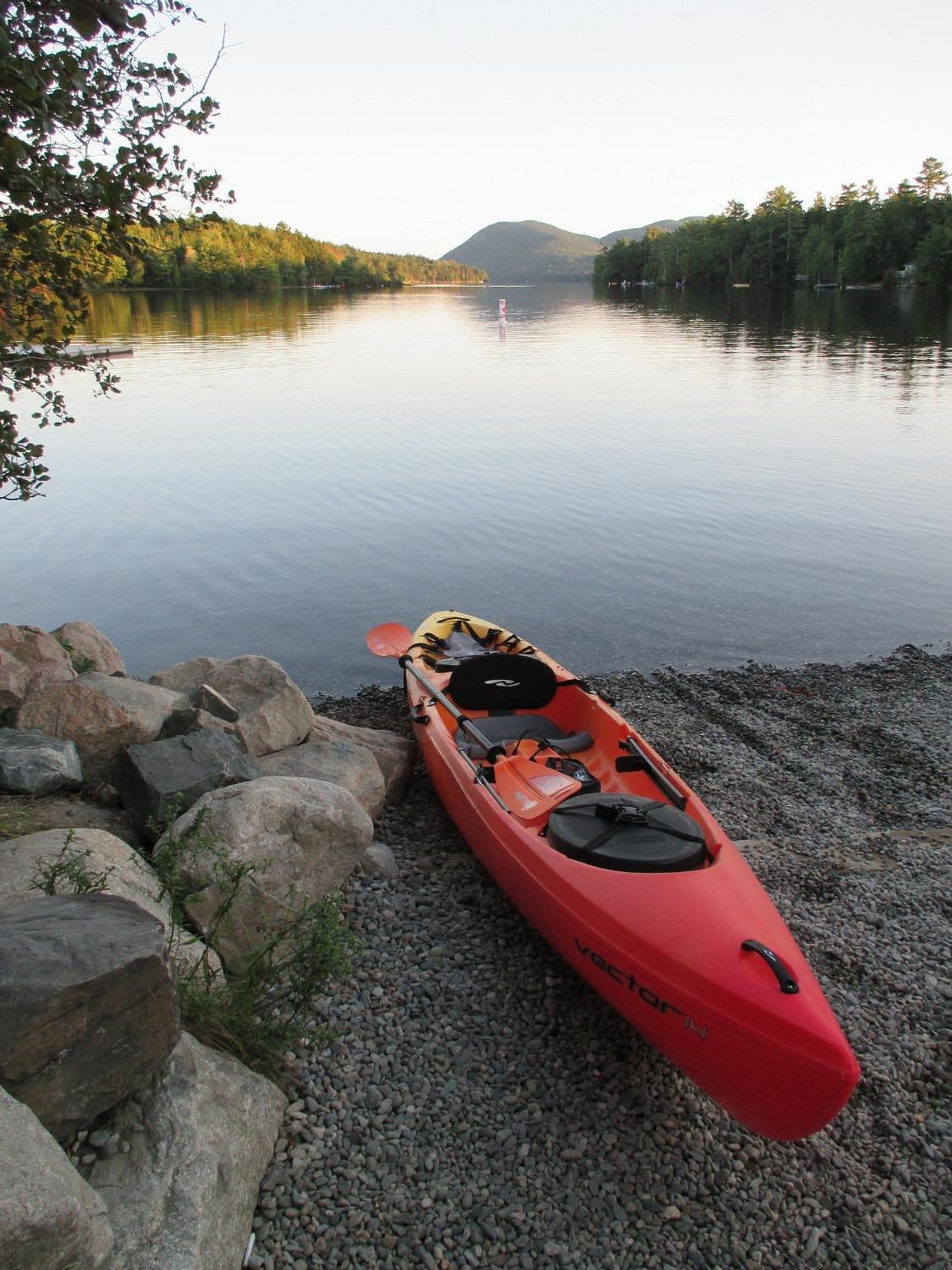 A red kayak rests on the rocky shoreline at Echo Lake in Acadia National Park, Maine.