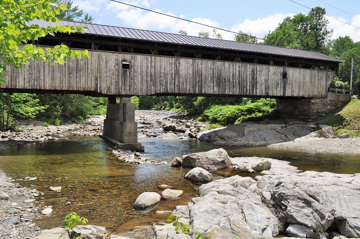 The Swiftwater covered bridge crosses the rocky river near the swimming area.