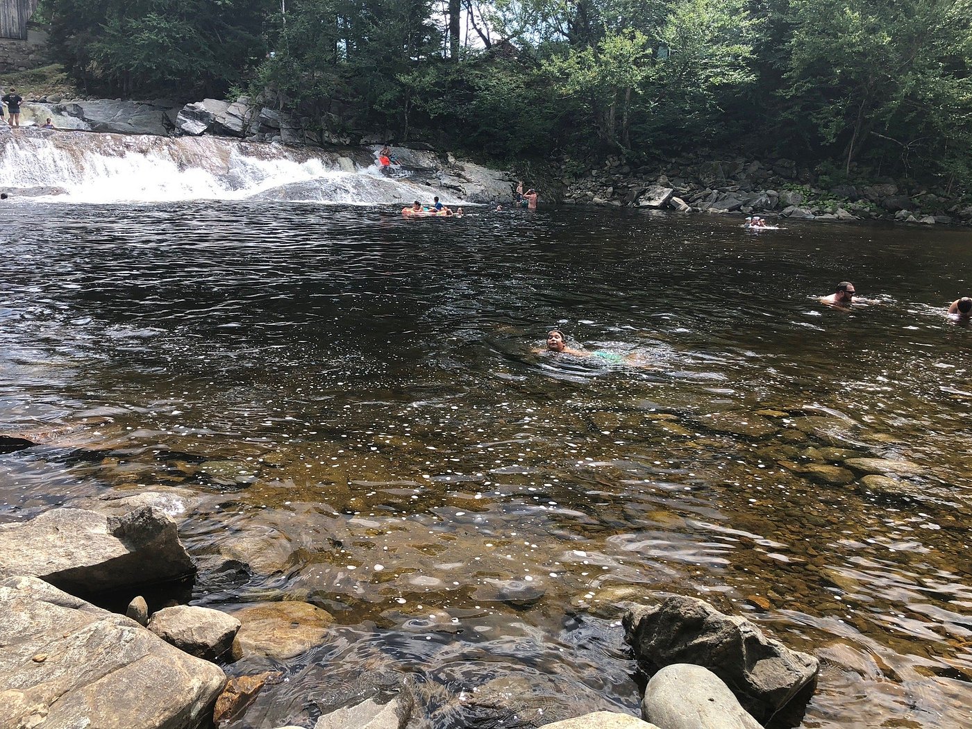 Swimmers use the clear river pool below Swiftwater Falls.