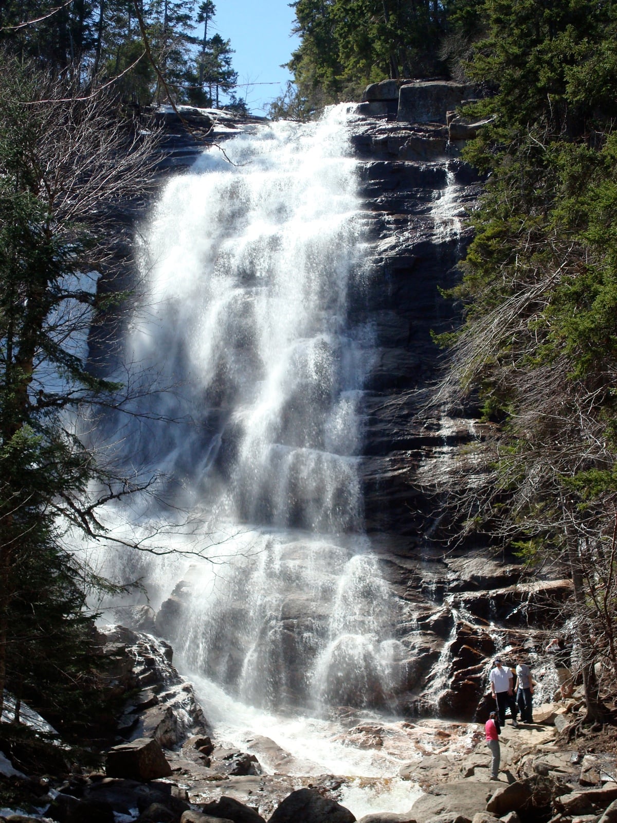 Water sheets across ledged rock on the side of Arethusa Falls.