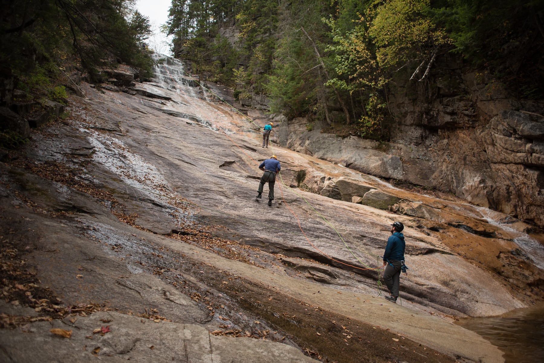 Climbers rappelling beside the sloping granite face at Ripley Falls in New Hampshire.