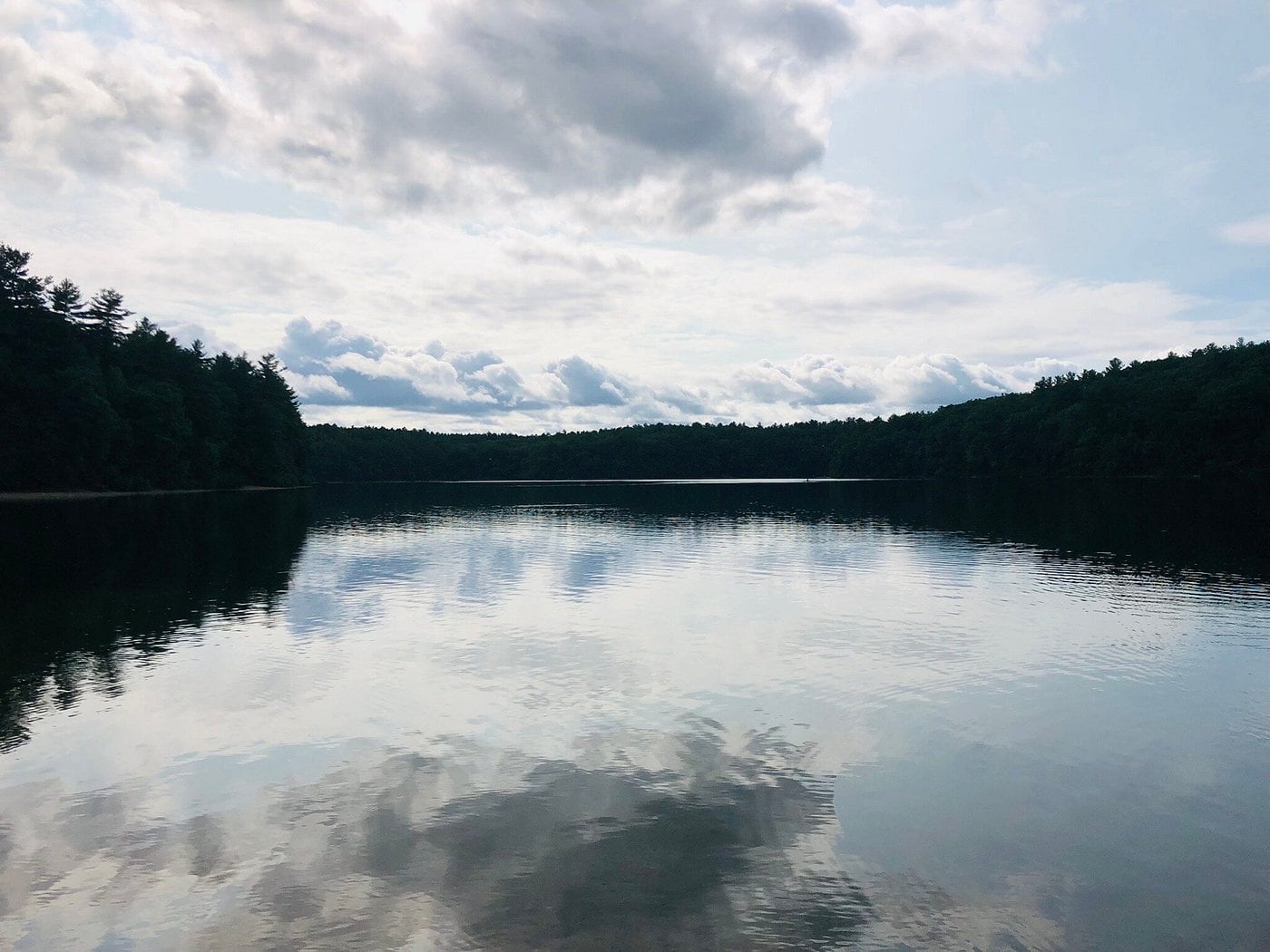 Clouds reflected on the calm surface of Walden Pond in Concord, Massachusetts.